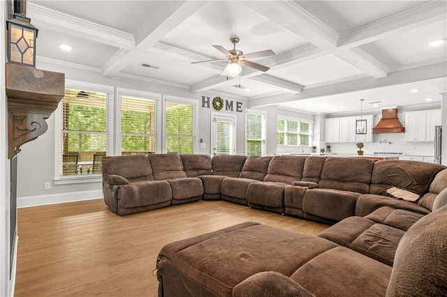 living room featuring coffered ceiling, light wood finished floors, healthy amount of natural light, beamed ceiling, and ornamental molding