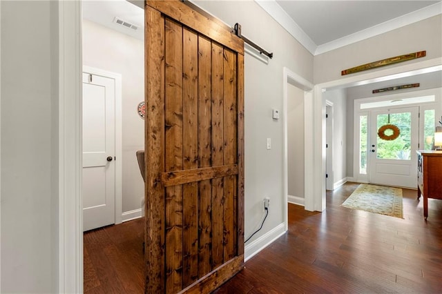 entryway with ornamental molding, dark hardwood / wood-style flooring, and a barn door