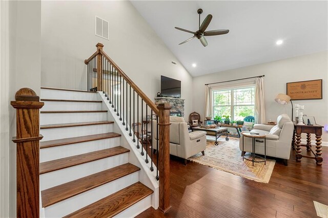 staircase with hardwood / wood-style flooring, ceiling fan, and high vaulted ceiling