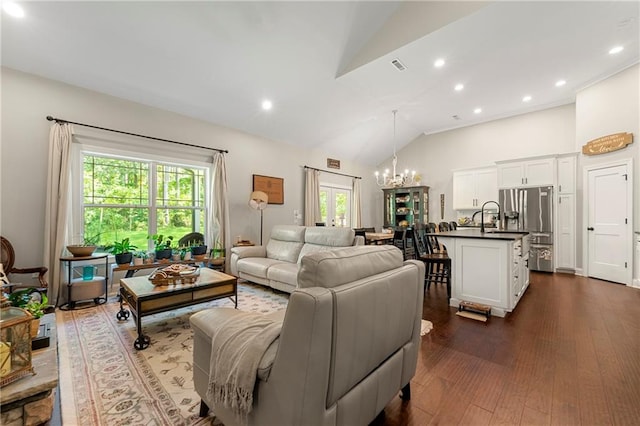 living room with lofted ceiling, a healthy amount of sunlight, dark hardwood / wood-style floors, and an inviting chandelier