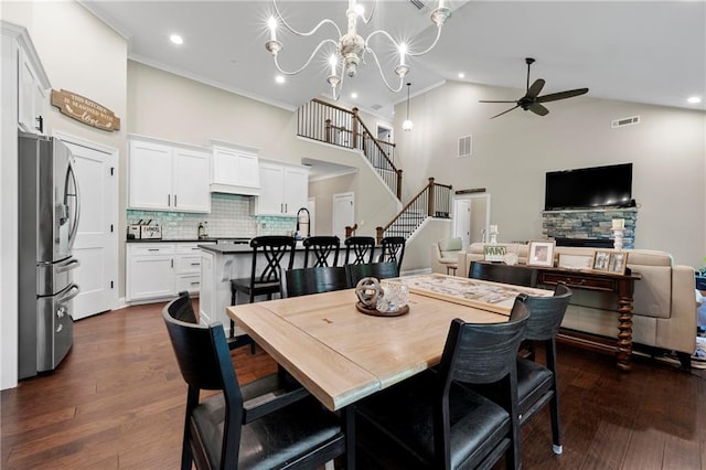 dining area with dark wood-type flooring, high vaulted ceiling, ornamental molding, and ceiling fan with notable chandelier