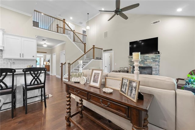 living room featuring dark hardwood / wood-style flooring, high vaulted ceiling, ornamental molding, and a fireplace