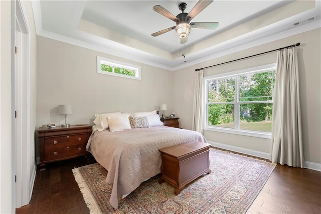 bedroom featuring dark wood-type flooring, ceiling fan, multiple windows, and a raised ceiling