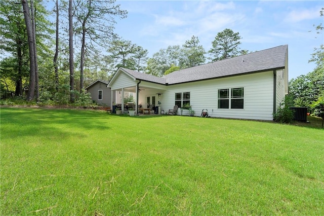 rear view of property featuring central AC unit, a lawn, and a patio area