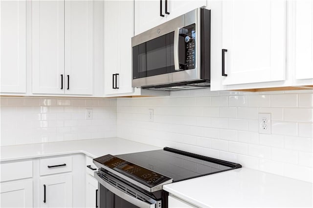kitchen featuring light countertops, stainless steel microwave, decorative backsplash, electric range oven, and white cabinets