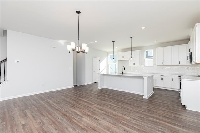 kitchen featuring a kitchen island with sink, dark wood-style floors, tasteful backsplash, and a chandelier