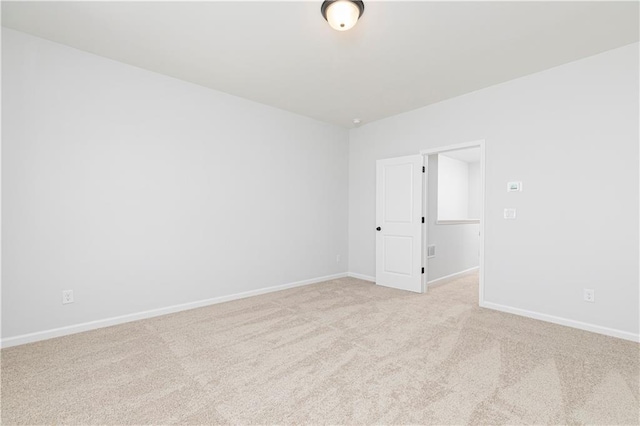 spare room with baseboards and light colored carpet