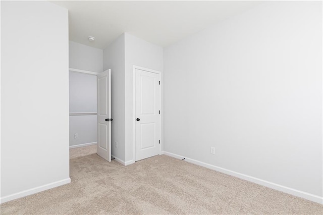 unfurnished bedroom featuring light carpet and baseboards
