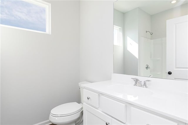 bathroom with a shower, toilet, vanity, and baseboards