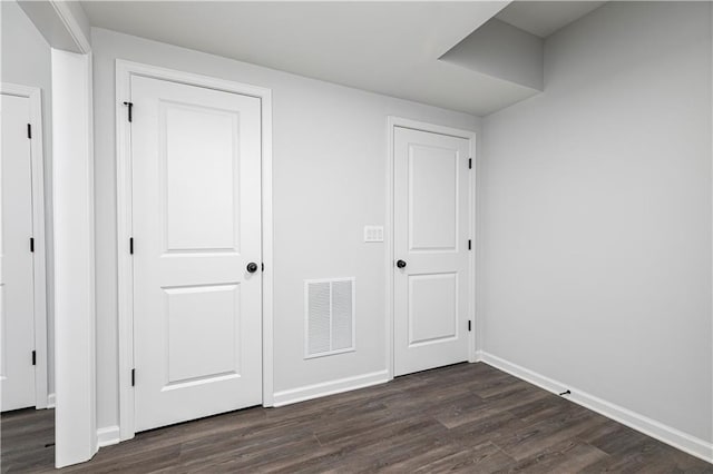 unfurnished bedroom featuring dark wood-type flooring, baseboards, and visible vents