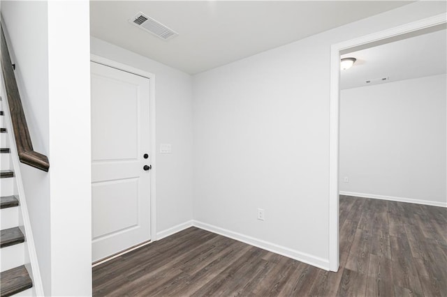spare room featuring baseboards, visible vents, stairway, and dark wood-type flooring