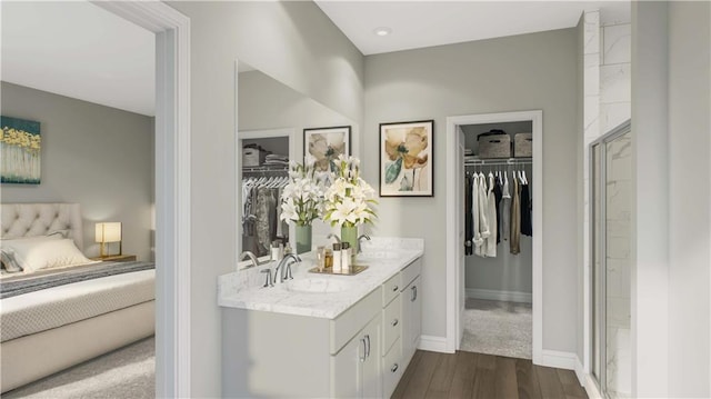 full bath with double vanity, wood finished floors, a shower with door, a sink, and ensuite bath