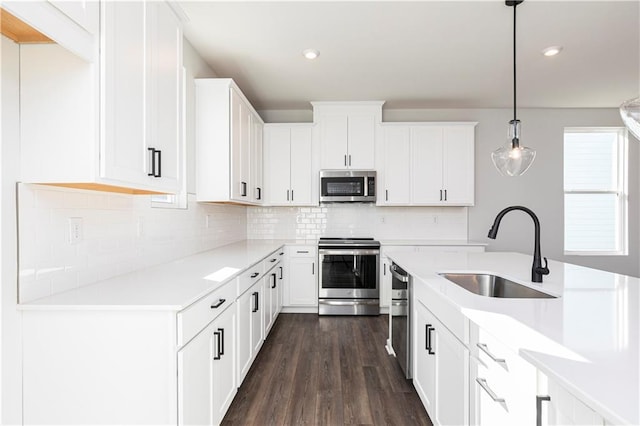 kitchen featuring light countertops, a sink, dark wood finished floors, stainless steel appliances, and decorative backsplash