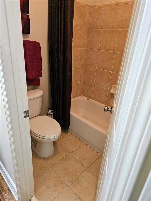 bathroom featuring toilet, tile patterned flooring, and shower / bath combo