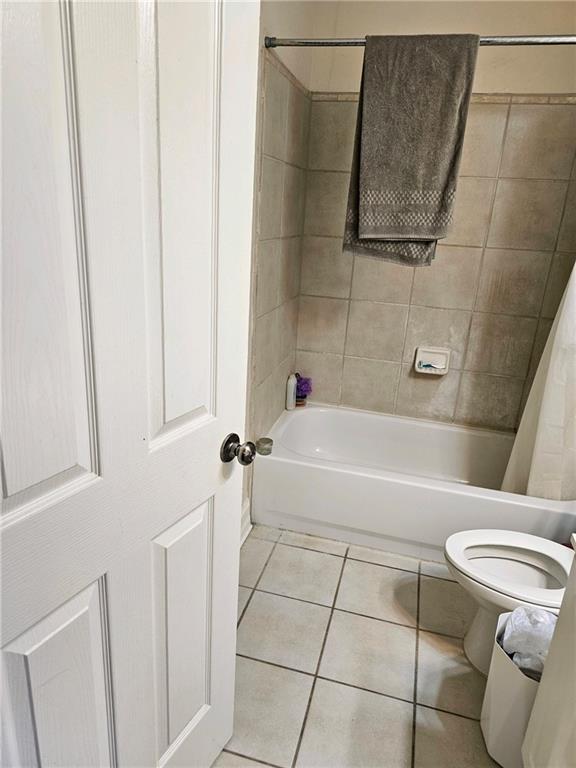 bathroom with tile patterned flooring, toilet, and shower / bathtub combination with curtain