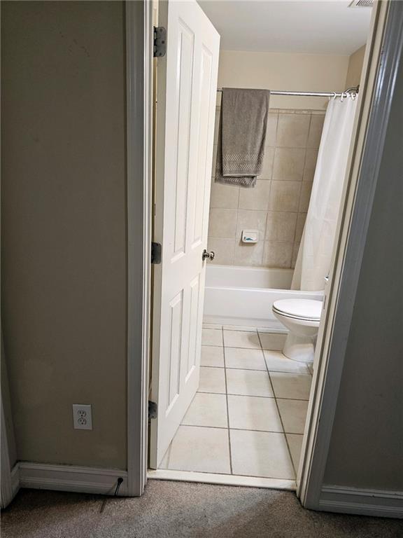 bathroom with shower / bath combination with curtain, tile patterned floors, and toilet