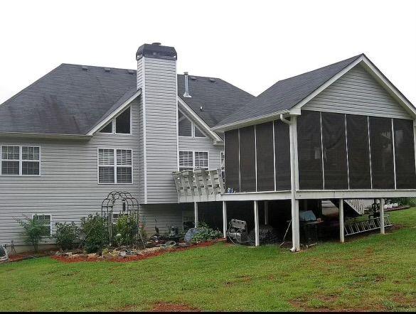 back of house with a lawn, a sunroom, and a chimney