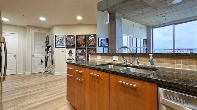 3300 Windy Ridge Parkway SE Unit 1121, Atlanta, GA 30339 - kitchen with a sink, brown cabinetry, light wood finished floors, dishwasher, and dark stone countertops