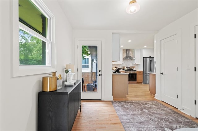 1494 May Ave SE, Atlanta, GA 30316 - kitchen with appliances with stainless steel finishes, wall chimney range hood, light wood-style floors, white cabinets, and backsplash