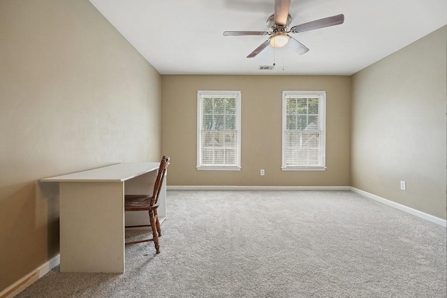 unfurnished office with a ceiling fan, light colored carpet, visible vents, and baseboards