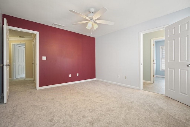 unfurnished room with light colored carpet, visible vents, ceiling fan, and baseboards