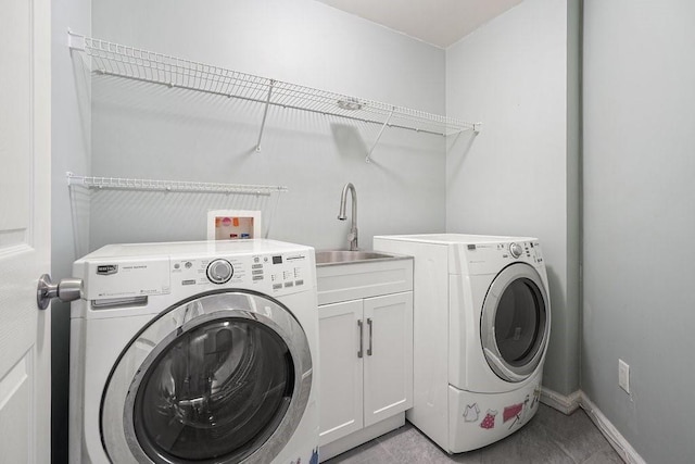 clothes washing area with independent washer and dryer, a sink, cabinet space, and baseboards