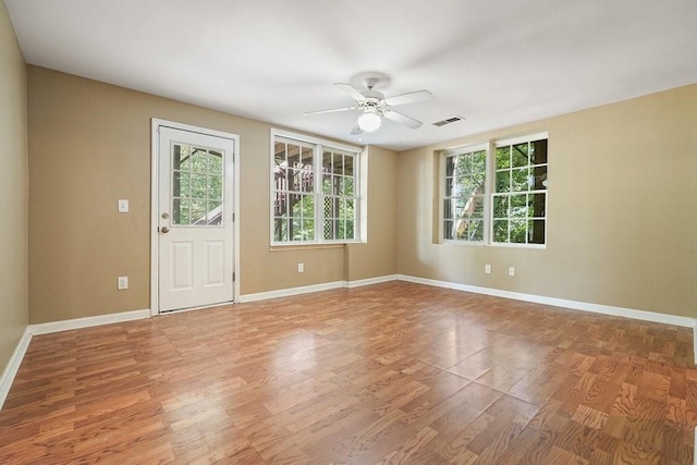 spare room with a ceiling fan, baseboards, visible vents, and wood finished floors