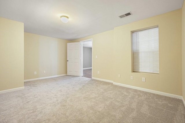 empty room featuring light carpet, baseboards, and visible vents