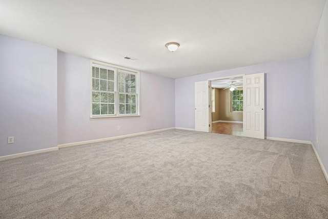 spare room featuring carpet floors, visible vents, and baseboards