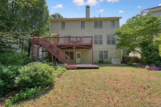 rear view of house featuring a wooden deck, a chimney, stairway, fence, and a yard