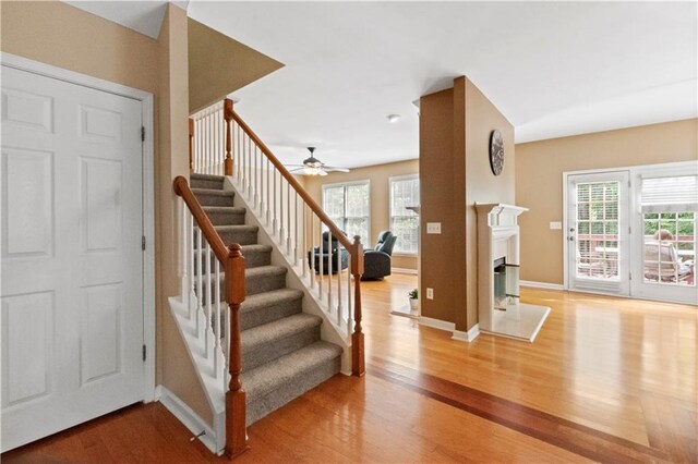 unfurnished living room with recessed lighting, baseboards, stairway, light wood finished floors, and a glass covered fireplace