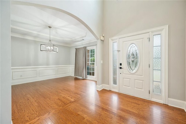 5635 Upper Creek Ct, Suwanee, GA 30024 - foyer entrance featuring arched walkways, wood finished floors, a chandelier, ornamental molding, and a wainscoted wall