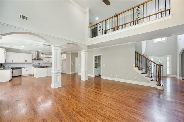 5635 Upper Creek Ct, Suwanee, GA 30024 - unfurnished living room with a high ceiling, light wood-style floors, decorative columns, stairway, and baseboards