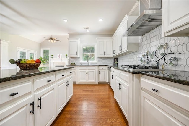 5635 Upper Creek Ct, Suwanee, GA 30024 - kitchen with wall chimney range hood, a ceiling fan, decorative backsplash, white cabinets, and light wood-style flooring