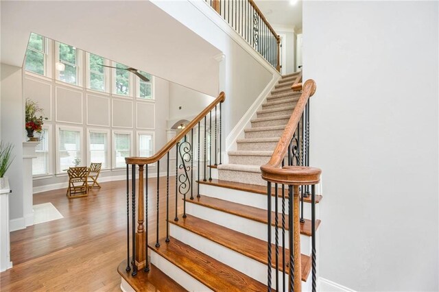 5635 Upper Creek Ct, Suwanee, GA 30024 - stairway featuring healthy amount of natural light, wood finished floors, a towering ceiling, baseboards, and a ceiling fan