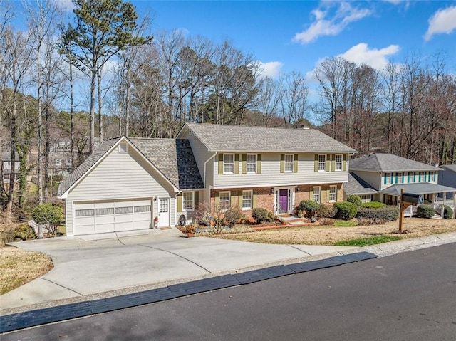 colonial-style house featuring a garage, concrete driveway, and brick siding