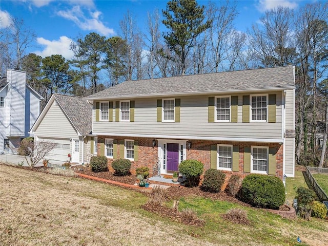 colonial home with a garage, a front yard, fence, and brick siding