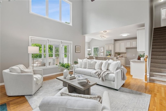 living area featuring stairs, a wealth of natural light, and light wood-style floors