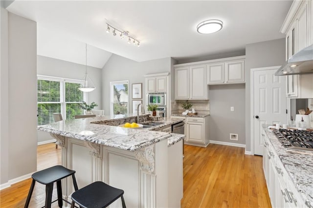 kitchen with light wood-style floors, appliances with stainless steel finishes, lofted ceiling, and a sink