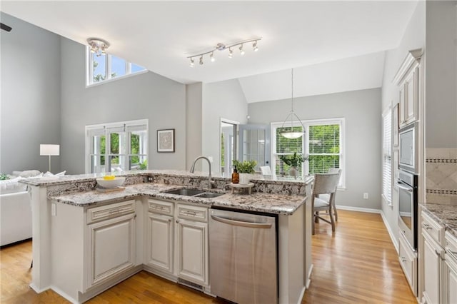 kitchen with plenty of natural light, appliances with stainless steel finishes, vaulted ceiling, and a sink