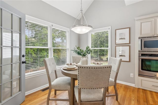 dining space featuring light wood finished floors, lofted ceiling, baseboards, and visible vents