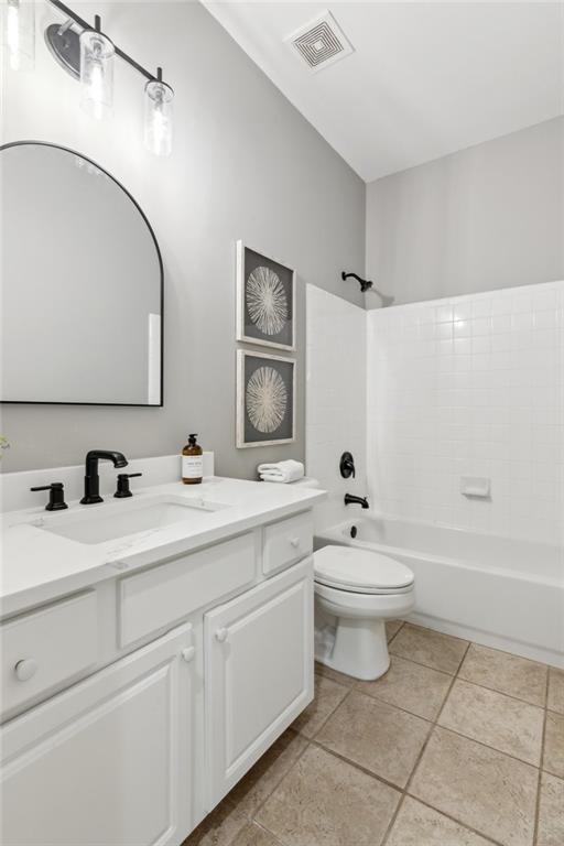bathroom featuring toilet,  shower combination, visible vents, tile patterned flooring, and vanity