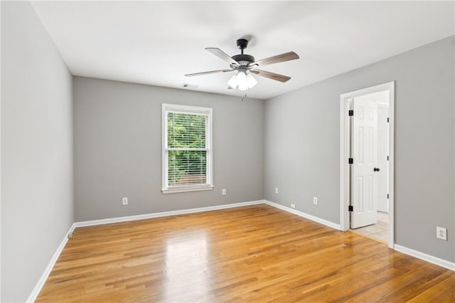 spare room featuring light wood-style floors, visible vents, baseboards, and ceiling fan