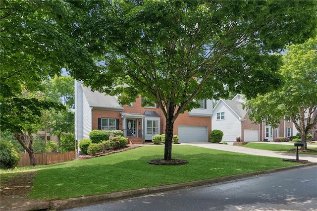traditional home with driveway, a front yard, fence, and an attached garage