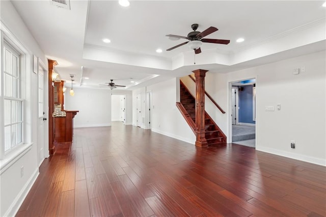unfurnished living room with a ceiling fan, stairway, and a tray ceiling