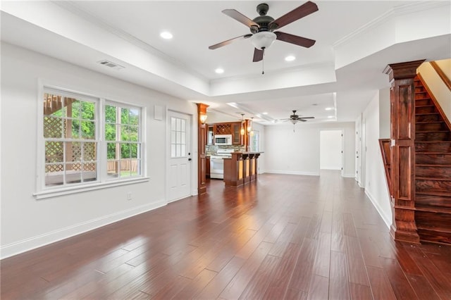 unfurnished living room with a ceiling fan, baseboards, visible vents, a raised ceiling, and stairway