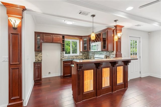 kitchen with a peninsula, backsplash, visible vents, and white microwave