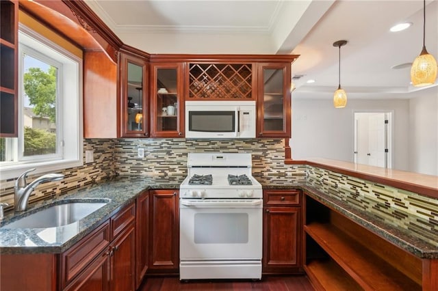 kitchen with a sink, dark stone counters, pendant lighting, white appliances, and tasteful backsplash