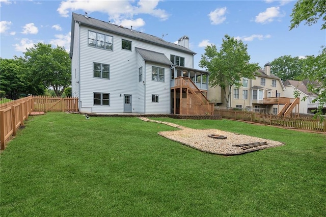 back of property with a fire pit, a chimney, a fenced backyard, and stairs