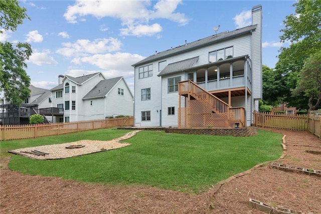 rear view of property with a fire pit, stairway, a fenced backyard, a chimney, and a lawn